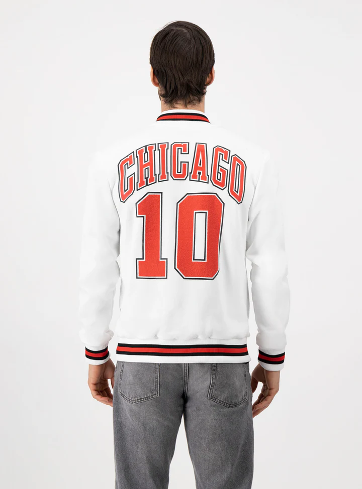 Hombre de espaldas usando sudadera beisbolera color blanco que dice CHICAGO 10 en letras naranjas.